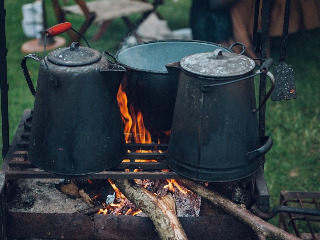 You’ll need saucepans of course! 
What to pack for campfire cooking. Here's a guide to show you that there's nothing worry about and some tips and tricks to make is all seem easy. 

Cooking over your campfire can be a daunting prospect for many less experienced campers, but making a campfire and cooking meals over it can be surprisingly simple. It is a great way to become more self-sufficient and have an authentic back-to-basics camping experience. 

I’d recommend starting with simple recipes using tin foil packets as well as having barbecues, then build up to some more complex recipes. The first step towards successful campfire cooking is having the right equipment. I’ll go through the top 12 items you should pack for campfire cooking to help you get started (with a printable campfire cooking checklist at the end).
Obviously, you’ll need some pots and pans for campfire cooking. 

You want at least one small pan, which can be used for anything from heating up milk for hot chocolate to heating through a can of beans, or even making cheese/chocolate fondue. For a guide to campfire fondue (a fantastically glamorous camping meal/dessert), take a look at The Chocolate or Cheese Fondue revolution. 

You’ll also need a big saucepan, especially if you’re going to be bulk cooking for loads of people. A big saucepan is essential for cooking stews and chillies over your campfire, and if you’d like some recipes for delicious camping stews and casseroles, here’s my general guide to camping stews.

Frying pan or skillet

A frying pan is another camping essential. 

A large sturdy frying pan is great for camping breakfasts as it can be used to make pancakes, french toast or even a fry-up. 

For tip on how to make a full English for a filling camping breakfast and some more interesting camping breakfast ideas, easy reading Campfire Breakfast in style.   

Although not essential, a cast iron skillet is more suitable than a normal frying pan for cooking over the campfire. Cast iron skillets have a heavy bottom and thick walls, which means they distribute heat more evenly and can better withstand the heat of the campfire. A skillet is key piece of cooking equipment for tons of camping recipes, including