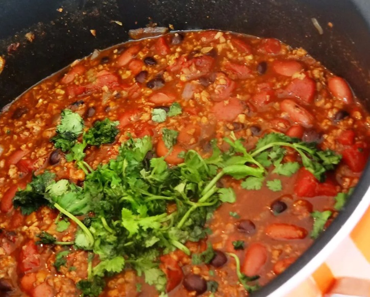 Campfire chilli is a fantastic warming meal that can be enjoyed whichever season you want and is also great for when you want to try your hand at cooking over the campfire. It is a one pot meal, so is super easy to cook for big groups and requires minimal washing up. Chilli can be vegetarian, or you can make chilli con carne if you’re camping with meat lovers. This blog contains recipes for both.  

Cooking on the campfire 

When cooking over your campfire, there are a few things it’s important to keep in mind. Let the campfire burn down to the white-hot coals before you start cooking the chilli, as cooking over bare flames will only burn your chilli and blacken the pan. 

If you’re cooking in an ordinary pan, you want place it on a grill or rack a couple of inches above the coals to cook over the campfire. 

But if you’re cooking in a dutch oven, just place it directly onto some pre-heated coals. 

For a similar Mexican inspired dinner that can be cooked in a dutch oven, why not try out this recipe for Dutch oven Enchiladas.

Vegan / Vegetable Chilli 

For this simple vegan chilli recipe:

Start by chopping 2 onions, one red and one green pepper. 

Then fry the onions and peppers in a large pan over your campfire for about 8 minutes. 

Add 1 tsp cumin and 1 tsp smoked paprika, two crushed cloves of garlic and either ½ tsp cayenne pepper or a deseeded chopped chilli if you like your chilli spicier. 

Sauté for one minute or until the spices release their aromas. 

Then add one tbsp tomato puree, and cook for another minute. 

Add a tin of chopped tomatoes and a drained 400g tin of cooked green lentils. 

Let it all cook for 30-45 minutes until the liquid has reduced.   

10 minutes before the end of cooking time, add a can of drained black beans. 

Once the chilli has finished cooking, remove from the heat and sprinkle with some chopped coriander. 

This recipe serves 3/4 depending on how big the portions are but is also a great recipe to scale up if you’re cooking for a large group. If you would like to cook for more people, then scale up the ingredients proportionately. The key to scaling up this recipe is just to make sure that you don’t add too many tomatoes, adding 2 tins chopped tomatoes only if you used 3 or 4 peppers.  

Pre-preparing the chilli 

If you’re super organised and would like to make some meals in advance to take camping with you, then vegetable chilli is a great option. It can be cooked in large quantities and keeps really well. You can make the chilli recipe above, or make good use of your oven, and roast some sweet potato chunks with spices to add to your chilli.   

Before you start cooking the chilli, add 2 chopped sweet potatoes to a roasting tin and toss with a drizzle of olive oil, some salt and pepper, 1 tsp smoked paprika and 1 tsp ground cumin. 

Roast for 25 minutes until cooked. 

Then add these sweet potato chunks to the chilli 10 minutes before it has finished cooking.

Chilli con carne 

To make this basic chilli con carne:

Start by heating one tbsp oil in a pan over your campfire. 

Add one chopped onion and cook until translucent, this should take around 5 mins. 

Then add 2 chopped garlic cloves, a chopped red pepper, 1 tsp mild/hot chilli powder, 1 tsp paprika and 1 tsp ground cumin. 

Stir to coat the veg in the spices and leave to cook for another 5 mins, stirring once or twice. 

Then add 500g lean minced beef, break up with your spoon and brown the mince in the hot pan until there aren’t any pink bits left.  

Next, crumble one beef stock cube into 300ml hot water and pour the stock into the pan. 

Add one 400g can chopped tomatoes, ½ tsp dried marjoram, 1 tsp sugar, 2 tbsp tomato puree, some salt and pepper and stir. 

Bring to the boil, stir again, and allow the chilli to bubble gently for 20 minutes. 

As the heat of the campfire can be quite hard to control, the chilli could get too hot. If is catching on the bottom of the pot or drying out, just add a few tablespoons of water. 

Once the chilli has been cooking for 20 mins, drain a can of kidney beans, add to the pot and cook for another 10 minutes. 

Season, and allow the chilli to stand for 10 minutes before serving to let the flavours to combine.

What to eat with your chilli 

You can keep it simple and have your plant-based chilli or chilli con carne on its own in a bowl. But why not also serve with some (plant based) yogurt, cheese, coriander, and a segment of lime on the side. 

If you have a bit more time on your hands, you could also make a salsa with chopped tomatoes, onion, coriander and lime juice. 

Or you could mash up some avocado, a few tomatoes, lime and coriander to make guacamole to eat with your chilli. 

Then you can serve the chilli with rice, either in big bowls for a deconstructed wrap, or in tortillas. 

You could also enjoy your chilli with a pitta bread or some tortilla chips.  

Another option is to have your chilli with jacket potatoes. 

Pierce a sweet or baking potato with a fork. Then wrap in some aluminium foil and bury the potato packet in the coals of your campfire. 

Do this before you start cooking the chilli to make sure everything is ready at the same time. Then leave the foil wrapped potatoes in the fire for around 45 minutes (although adjust this time depending on the size of your potatoes, and the temperature of the fire). 

Then once they’re cooked, allow to cool and cut open lengthways. 

If you prefer, then you could buy pre-cooked jacket potatoes. I find these in the frozen section and are perfect for camping holiday as they take about 20-30 mins in the fire coals for the best jacket potato and no hard uncooked bits.

Fill the baked potatoes with some butter, salt and pepper, and serve with a couple of spoonfuls of chilli.  